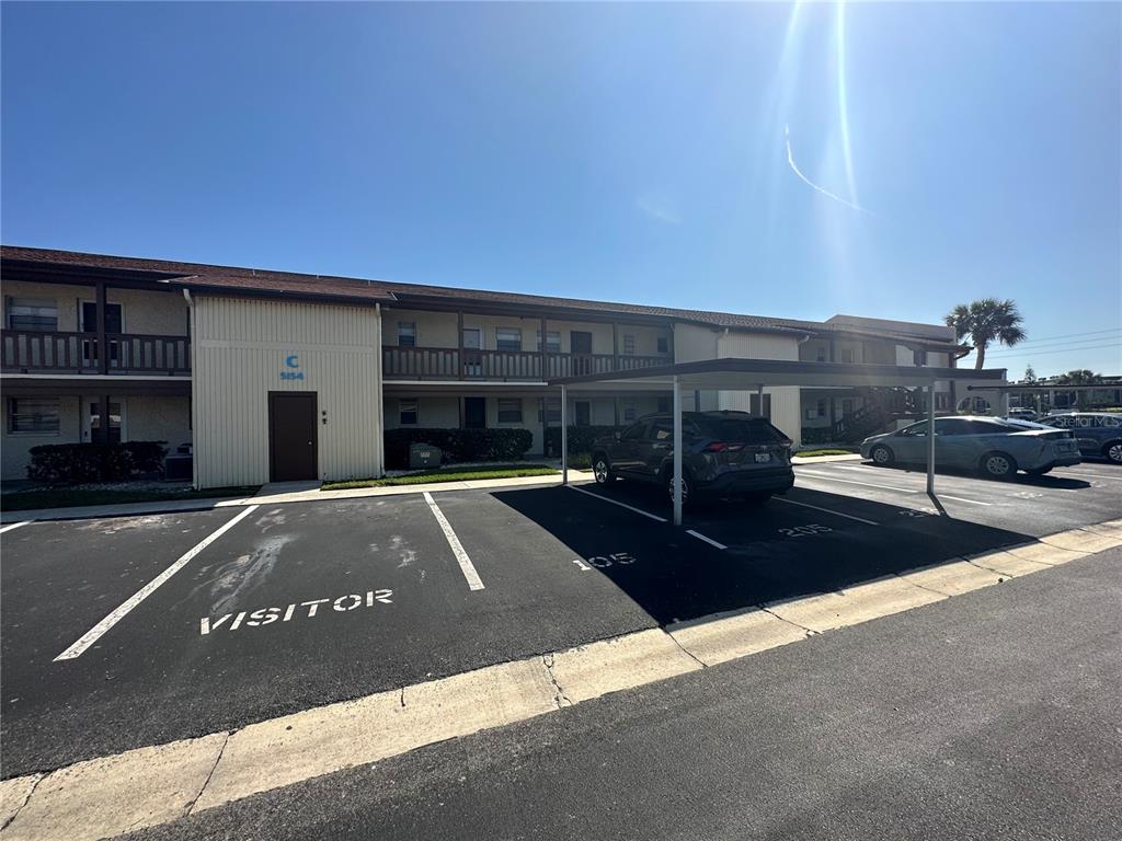 An exterior view of a two-story apartment building with a parking lot and covered spaces — 5154 TURQUOISE LANE UNIT 206, NEW PORT RICHEY, FL