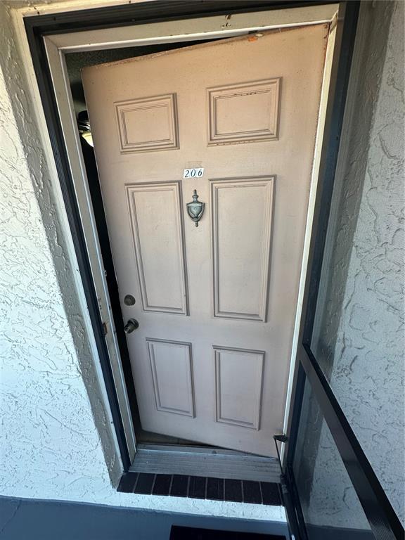 An exterior view of a beige six-panel door labeled 206 with a metal door knocker — 5154 TURQUOISE LANE UNIT 206, NEW PORT RICHEY, FL