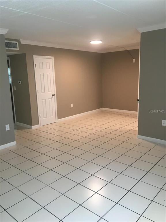 An empty room features light-colored square floor tiles and neutral-toned walls with a white door — 2 N FERNWOOD AVENUE UNIT 7, CLEARWATER, FL