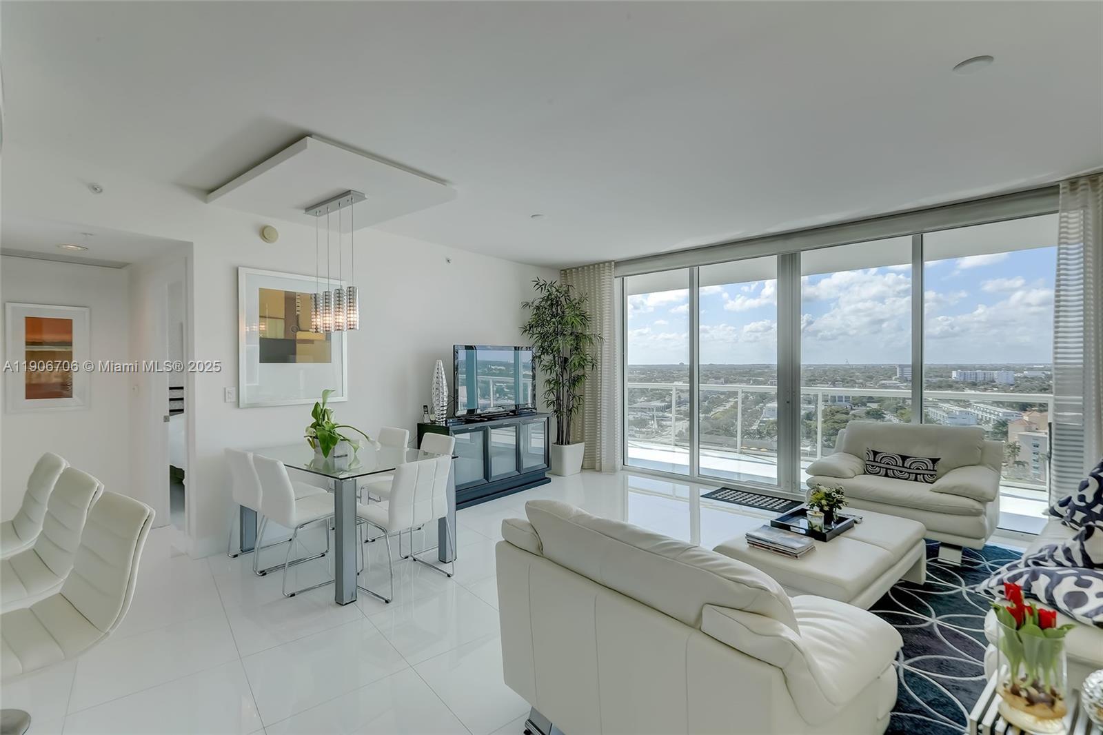 A modern living and dining area features white tile floors, floor-to-ceiling windows, and city views — 1 N Ocean Blvd # 1411, Pompano Beach FL 33062, POMPANO BEACH, FL