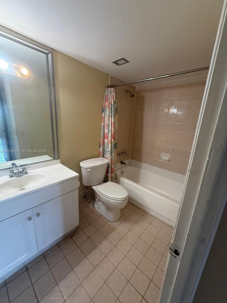 A bathroom features a white vanity, a toilet, and a shower-tub combination with tiled walls — MIAMI, FL