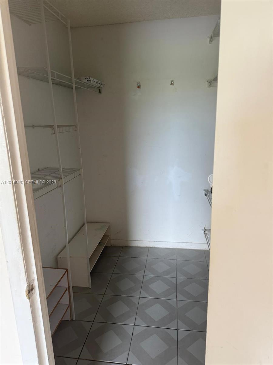 A walk-in closet with wire shelving, a small shoe rack, and gray tiled flooring — MIAMI, FL