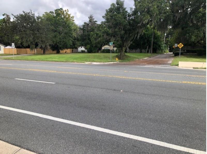 A vacant grassy lot sits adjacent to a paved road with a yellow traffic sign — 1202 NW 39TH AVENUE, GAINESVILLE, FL