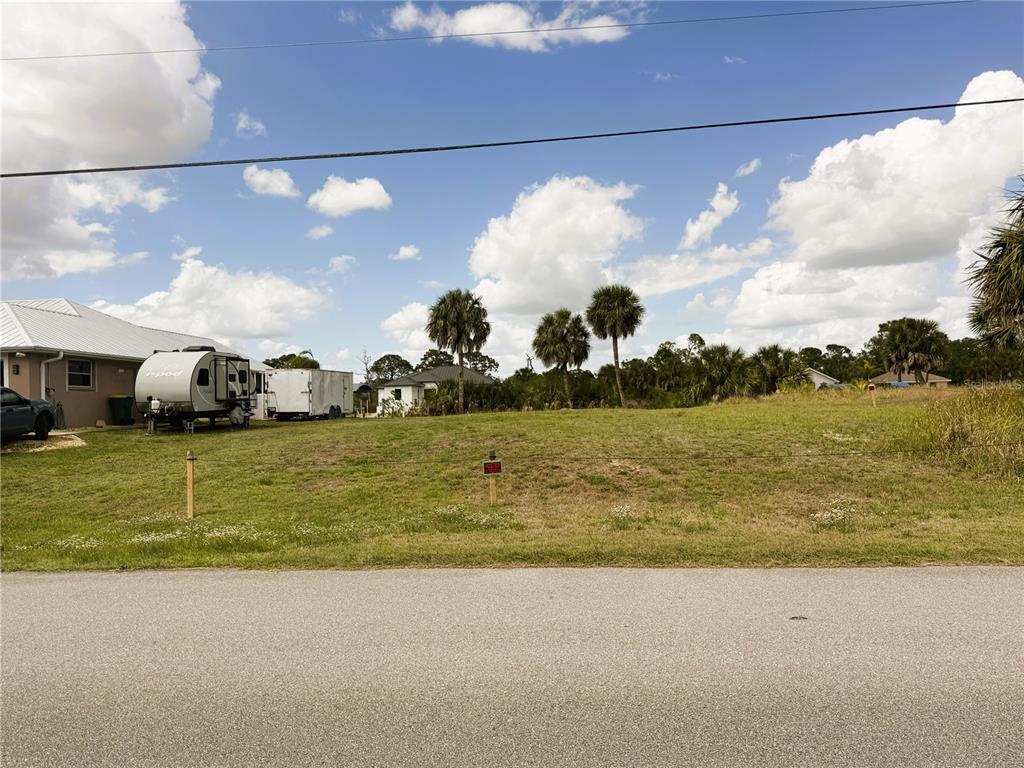 A vacant grassy lot sits next to a house with a parked travel trailer — 13572 WAINWRIGHT DRIVE, PORT CHARLOTTE, FL