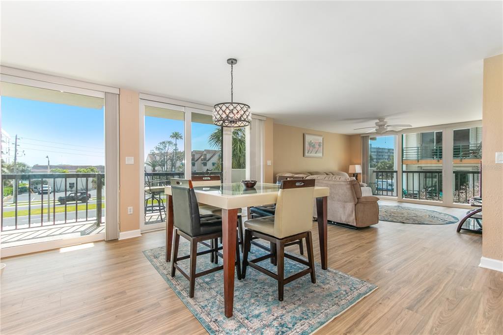 A dining area with a glass-topped table and chairs sits before sliding doors to balconies — 400 ISLAND WAY UNIT 212, CLEARWATER BEACH, FL