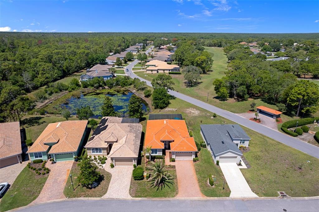 An aerial view shows several suburban houses with tiled roofs situated near a small pond — 8984 WADE STREET, WEEKI WACHEE, FL