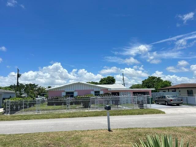 A pink, single-story house with a white roof sits behind a white metal fence — 14620 E Polk Street, Miami FL 33176, MIAMI, FL