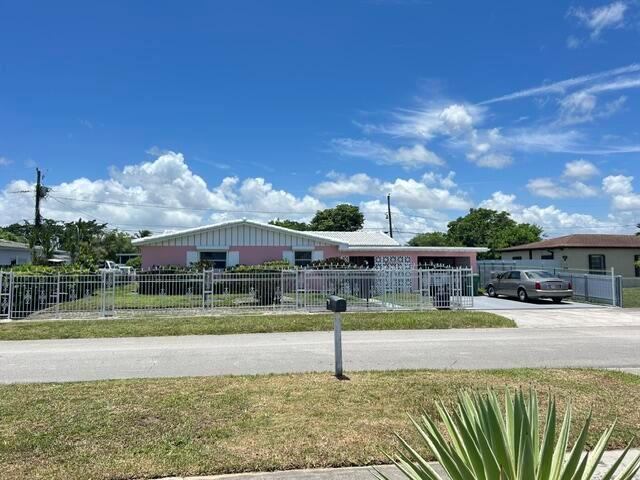 A pink single-story house with a white roof sits behind a metal fence — 14620 E Polk Street, Miami FL 33176, MIAMI, FL