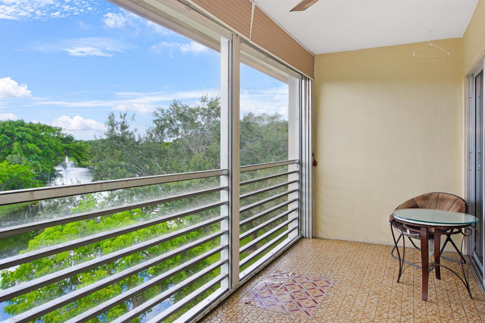 A kitchen with wood-grain cabinets, black appliances, white tile flooring, and a dining area — 2101 Lucaya Bend # D4, Coconut Creek FL 33066, COCONUT CREEK, FL