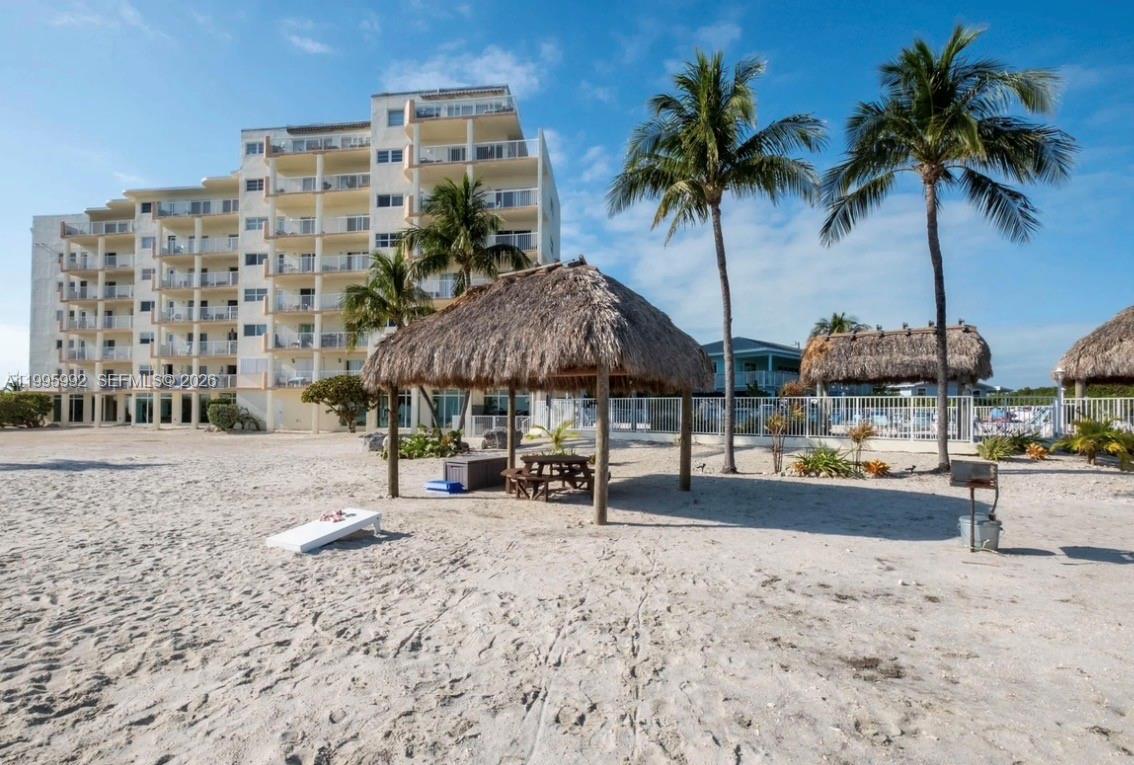 A sandy beach area features a thatched-roof tiki hut, picnic table, and a tall building — 200 Wrenn # 502, Plantation Key FL 33070, PLANTATION KEY, FL