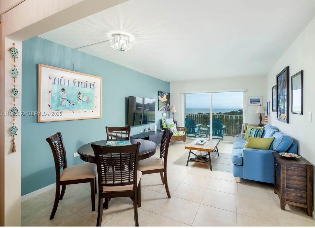 A living and dining area features a blue accent wall, tile floors, and balcony views — 200 Wrenn # 502, Plantation Key FL 33070, PLANTATION KEY, FL