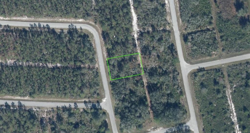 An aerial view shows a rectangular plot of land outlined in green amidst wooded terrain — 7524 YUMURI STREET, SEBRING, FL