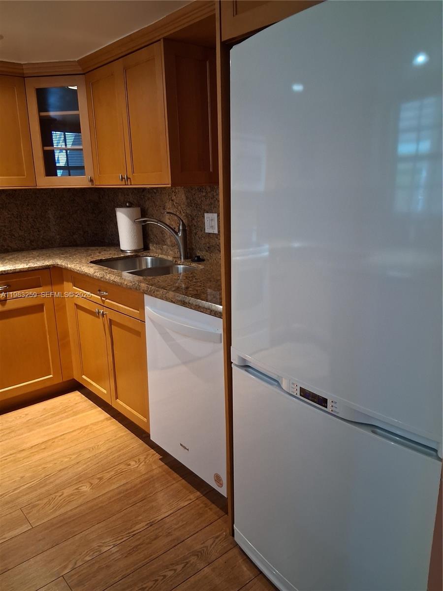 A kitchen features wood cabinets, granite countertops, a stainless steel sink, and white appliances — 7556 Stirling Rd # 123, Davie FL 33024, DAVIE, FL