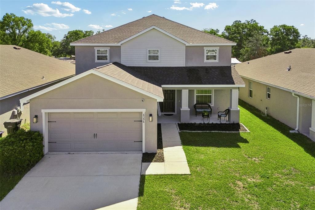 A two-story suburban house features a front-facing garage, a covered porch, and a grassy lawn — 6396 GARDNER DRIVE, LAKELAND, FL