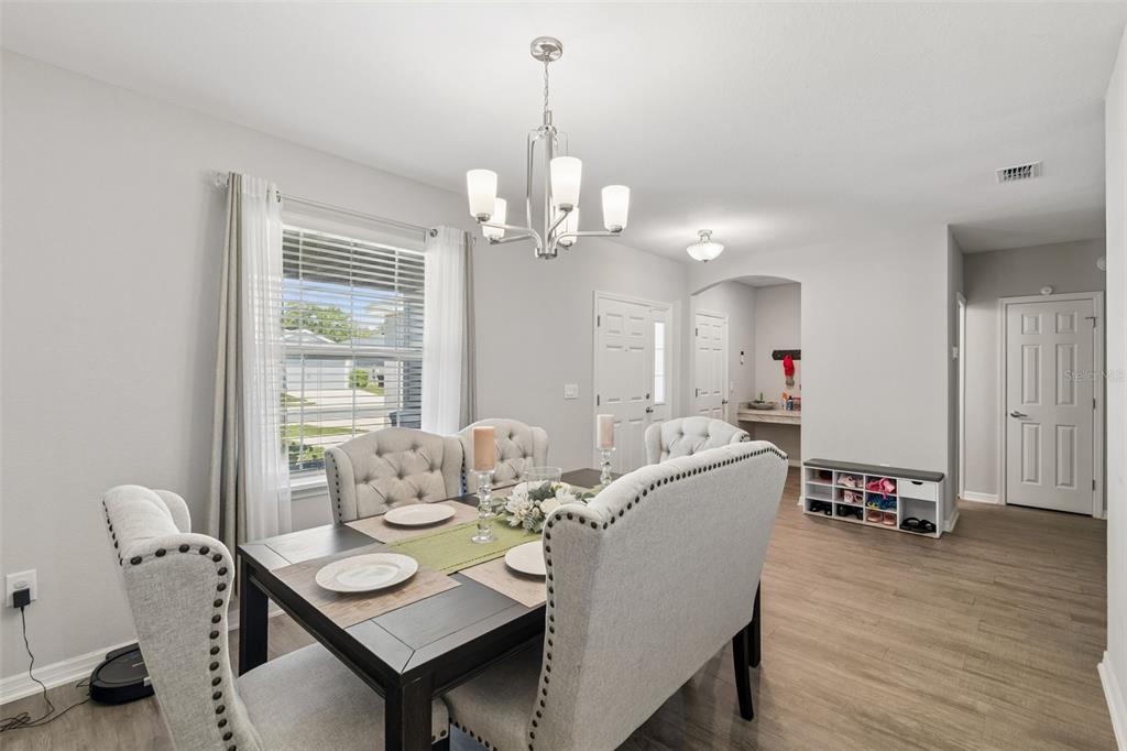 A dining room features a dark wood table, tufted chairs, and a modern chandelier — 6396 GARDNER DRIVE, LAKELAND, FL