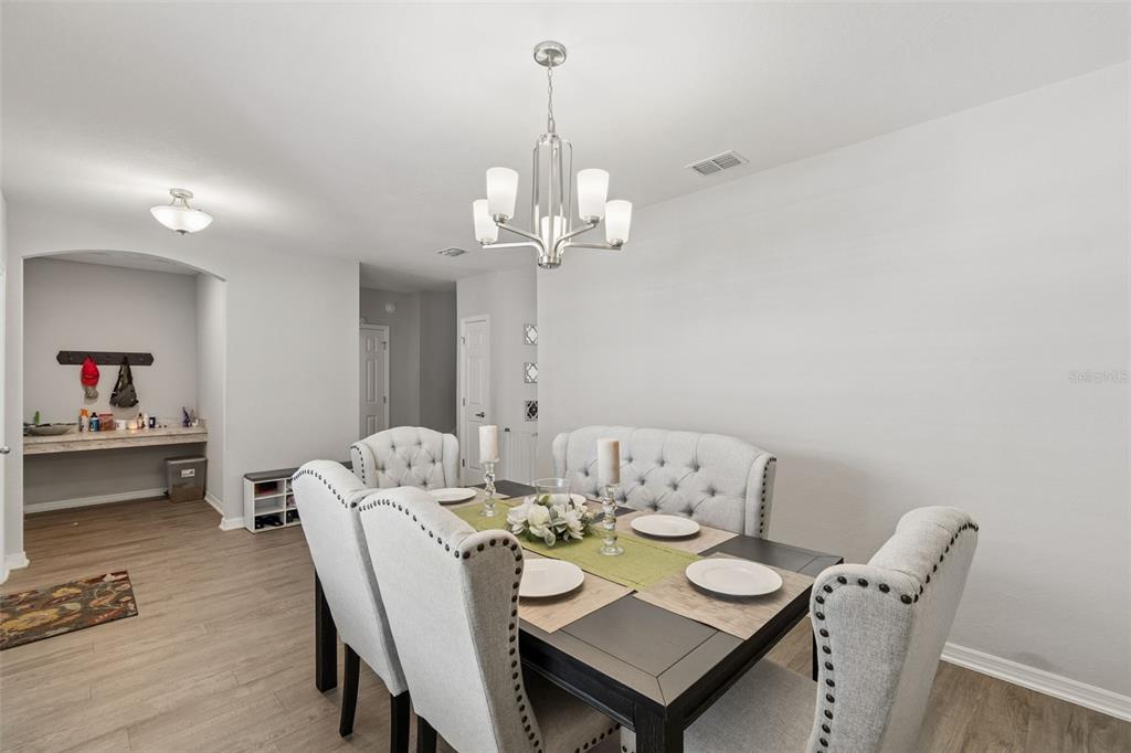 A dining room features a dark table, tufted chairs, a bench, and a modern chandelier — 6396 GARDNER DRIVE, LAKELAND, FL