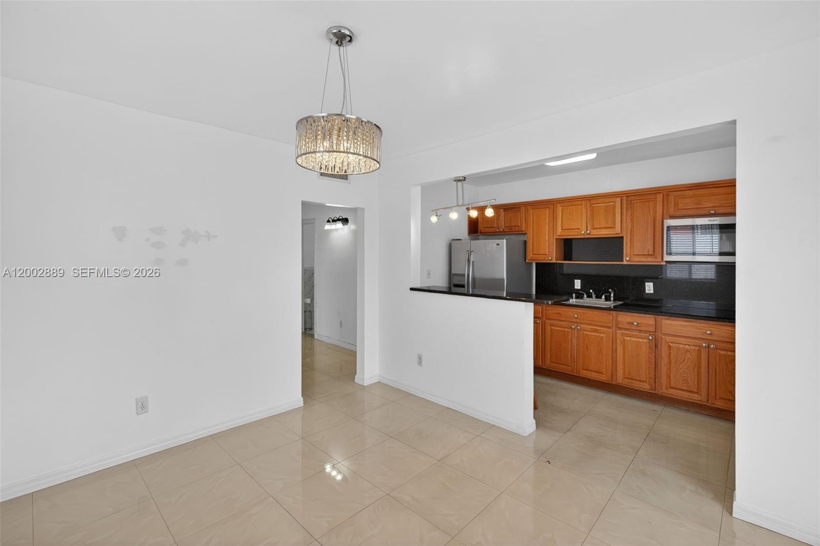 A dining area opens into a kitchen with wood cabinets and black countertops — 1130-1132 NW 34th Ave, Miami FL 33125, MIAMI, FL