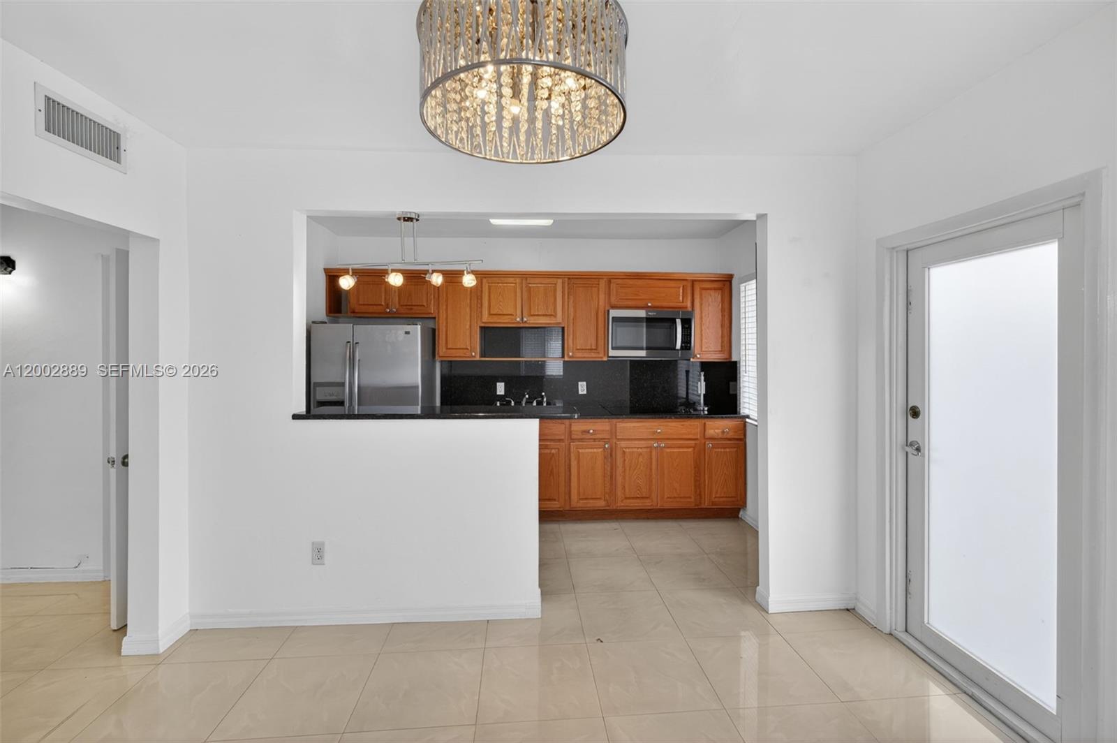 A kitchen with wood cabinets and a breakfast bar opens into a dining area — 1130-1132 NW 34th Ave, Miami FL 33125, MIAMI, FL