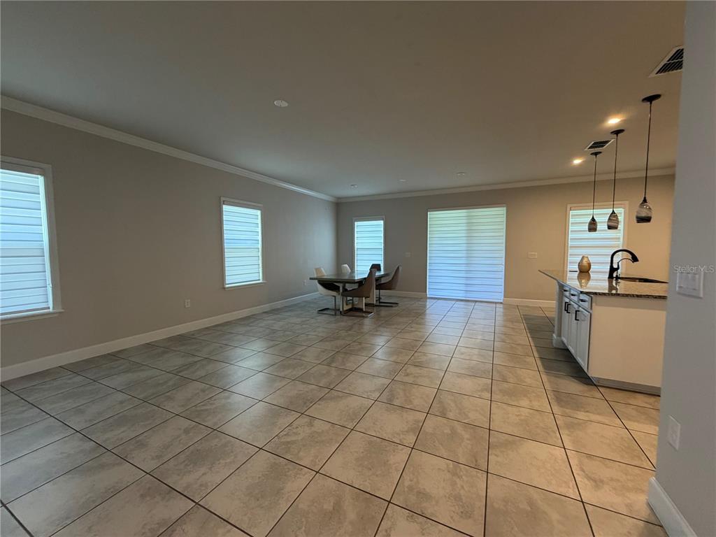 An open-concept kitchen and dining area features tile flooring, neutral walls, and pendant lighting — 2936 SLOUGH CREEK DRIVE, KISSIMMEE, FL