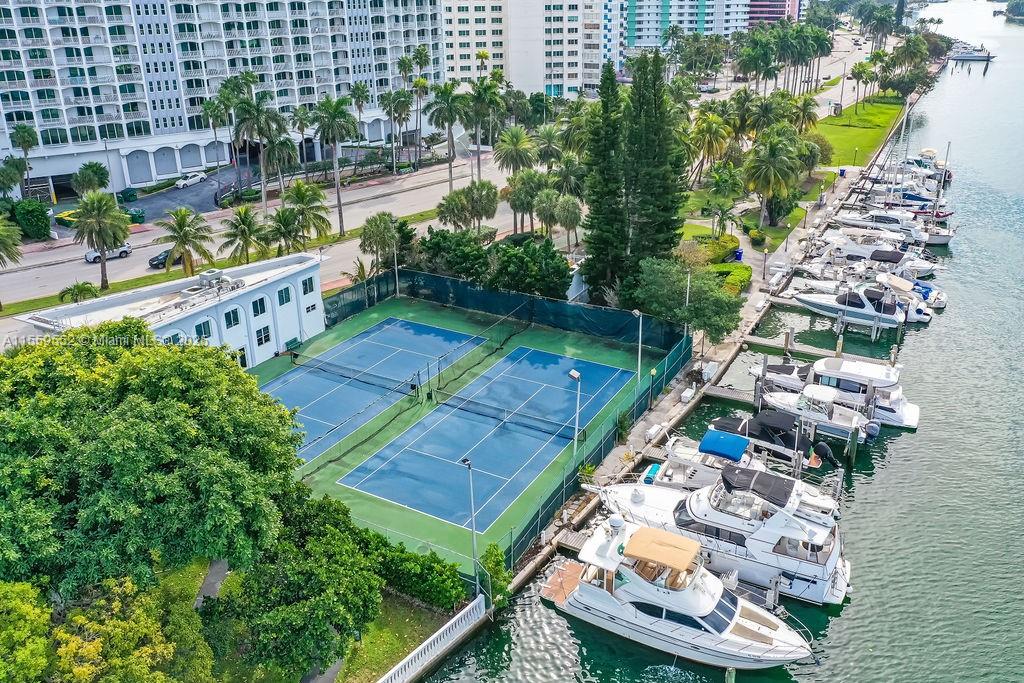 An aerial view shows two tennis courts situated between a residential building and a marina — 5401 Collins Ave # 209, Miami Beach FL 33140, MIAMI BEACH, FL