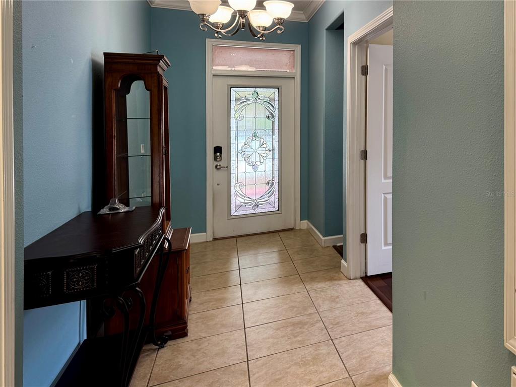 An entryway features a tiled floor, a glass-paneled front door, and a wooden display cabinet — 4056 SERENA LANE, CLERMONT, FL