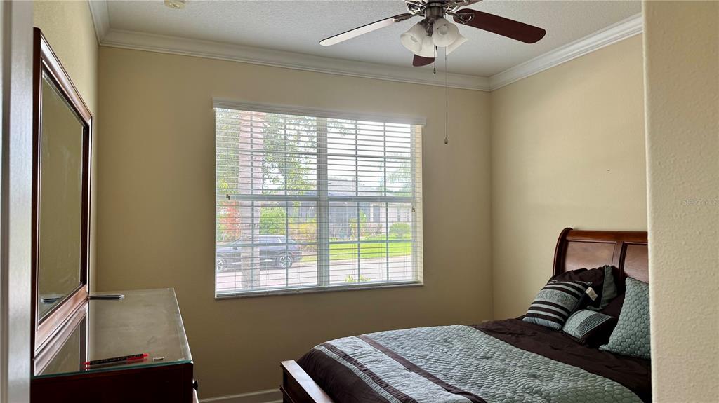 A bedroom features a bed with dark bedding, a dresser with a mirror, and a window — 4056 SERENA LANE, CLERMONT, FL