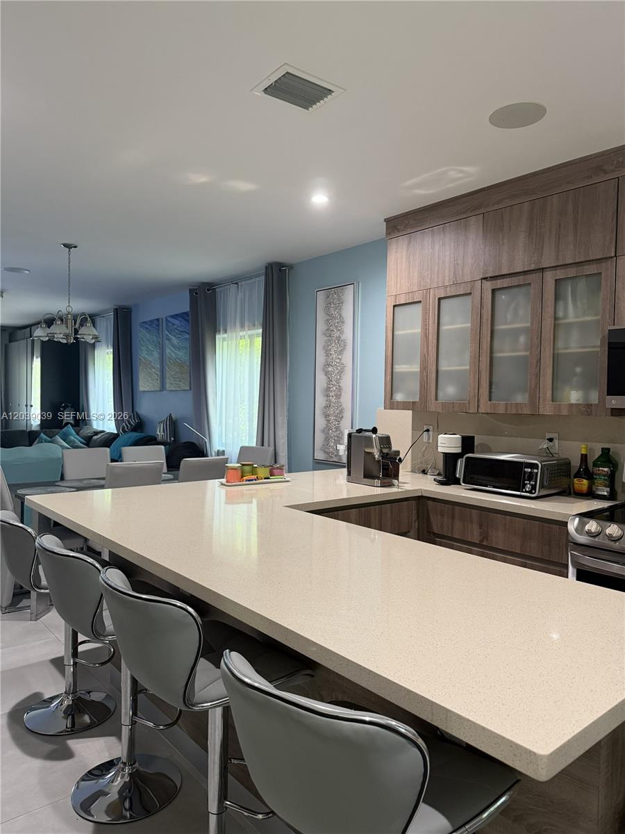 A kitchen features a large quartz island with bar seating and wood-toned cabinetry — KEY LARGO, FL