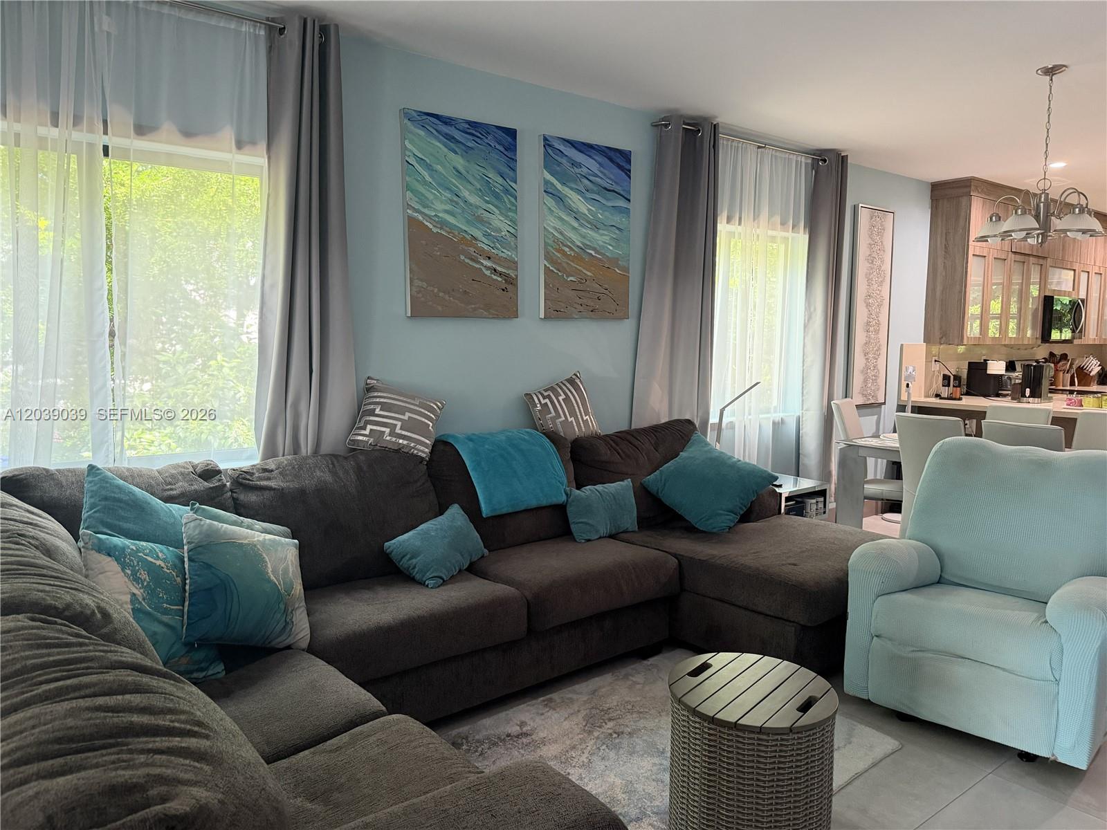 A living room features a dark sectional sofa, light blue accents, and an open kitchen area — KEY LARGO, FL