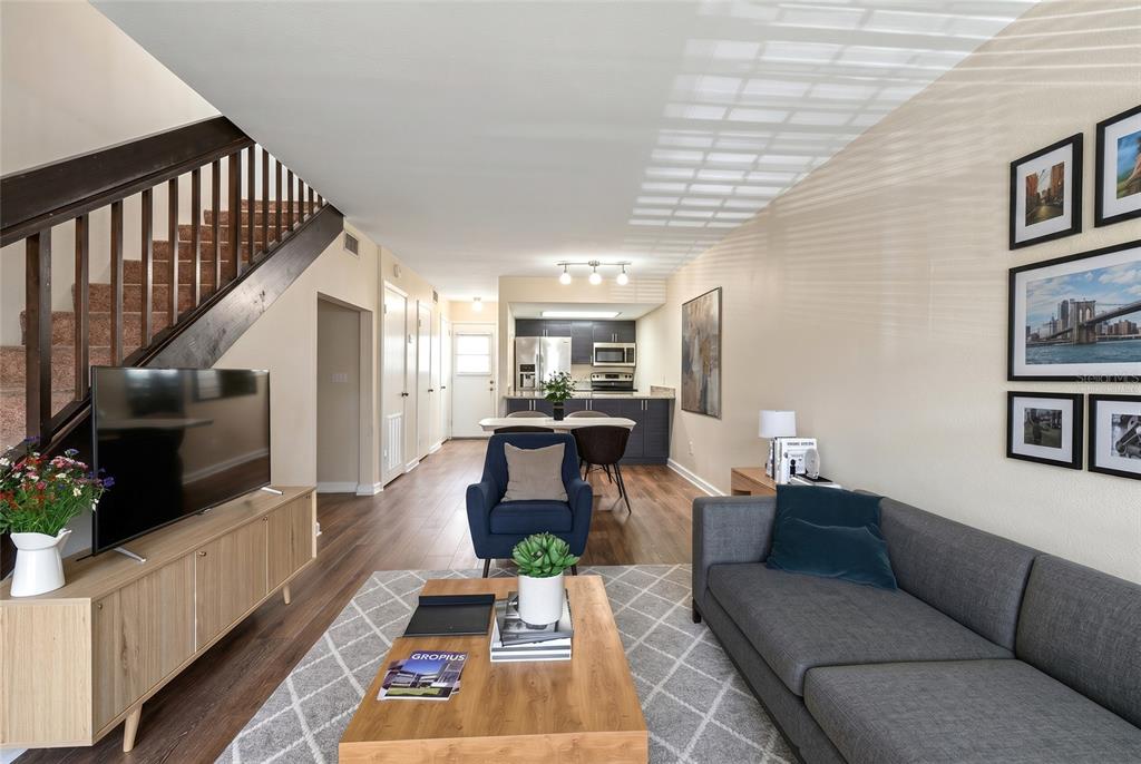 A living room with wood-look flooring, a staircase with dark railings, and a recessed alcove — 4839 MCELROY UNIT F206, TAMPA, FL