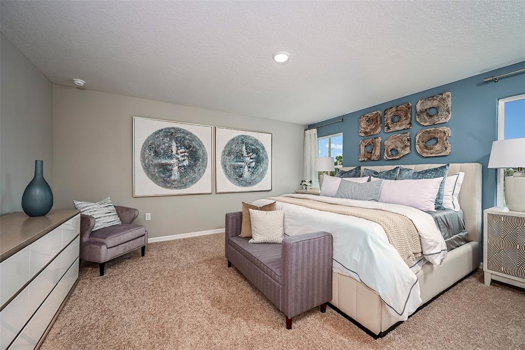 A bedroom features a blue accent wall, a king bed, and a gray armchair — 4365 RIVERBEND BOULEVARD, HAINES CITY, FL