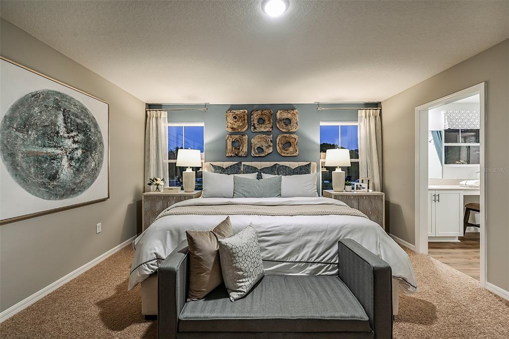 A bedroom features a king bed, a gray bench, and a blue accent wall — 4365 RIVERBEND BOULEVARD, HAINES CITY, FL