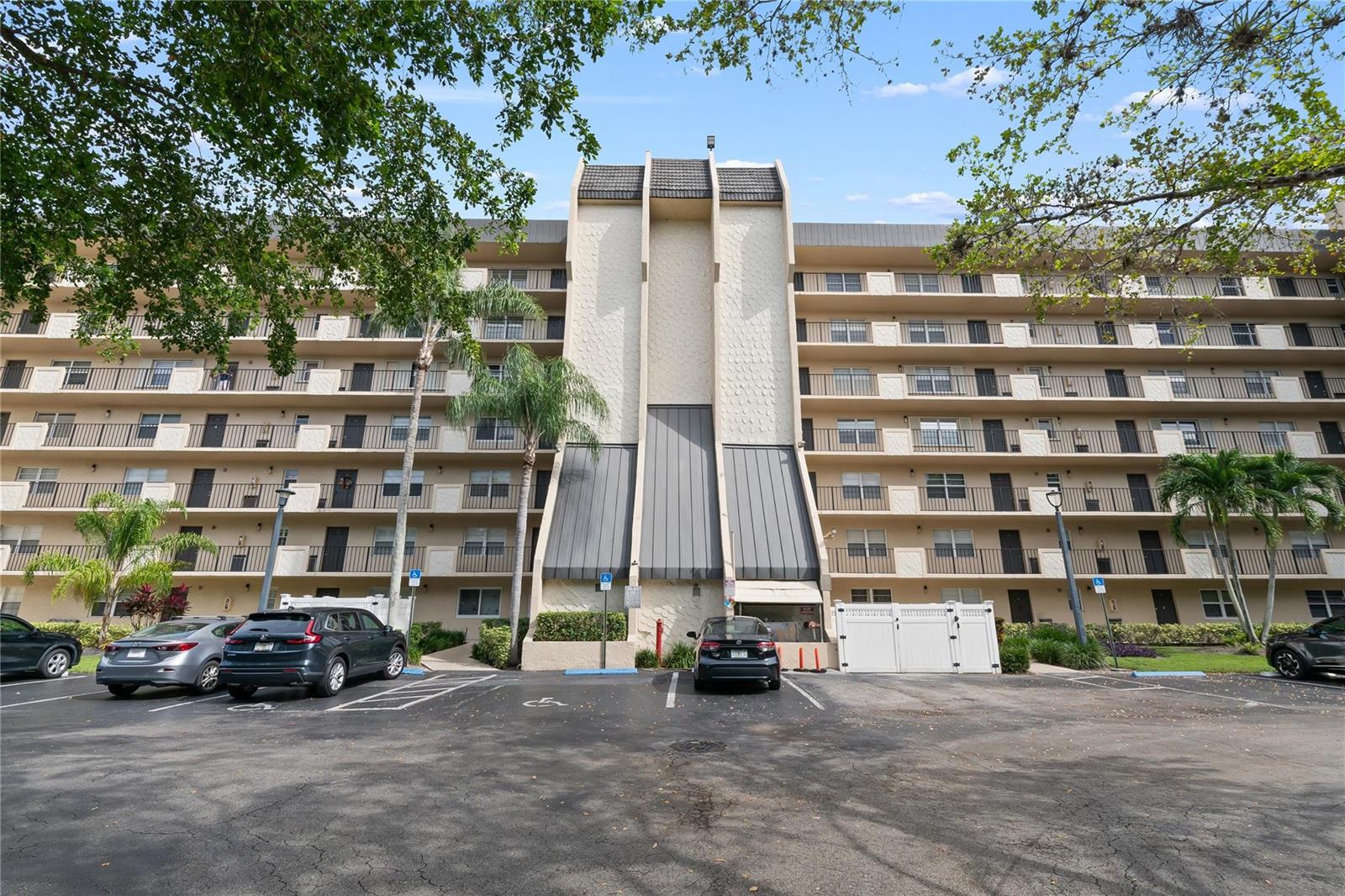 A multi-story apartment building features a central architectural facade with a parking lot in front — 3300 W Rolling Hills Circle # 610, Davie FL 33328, DAVIE, FL