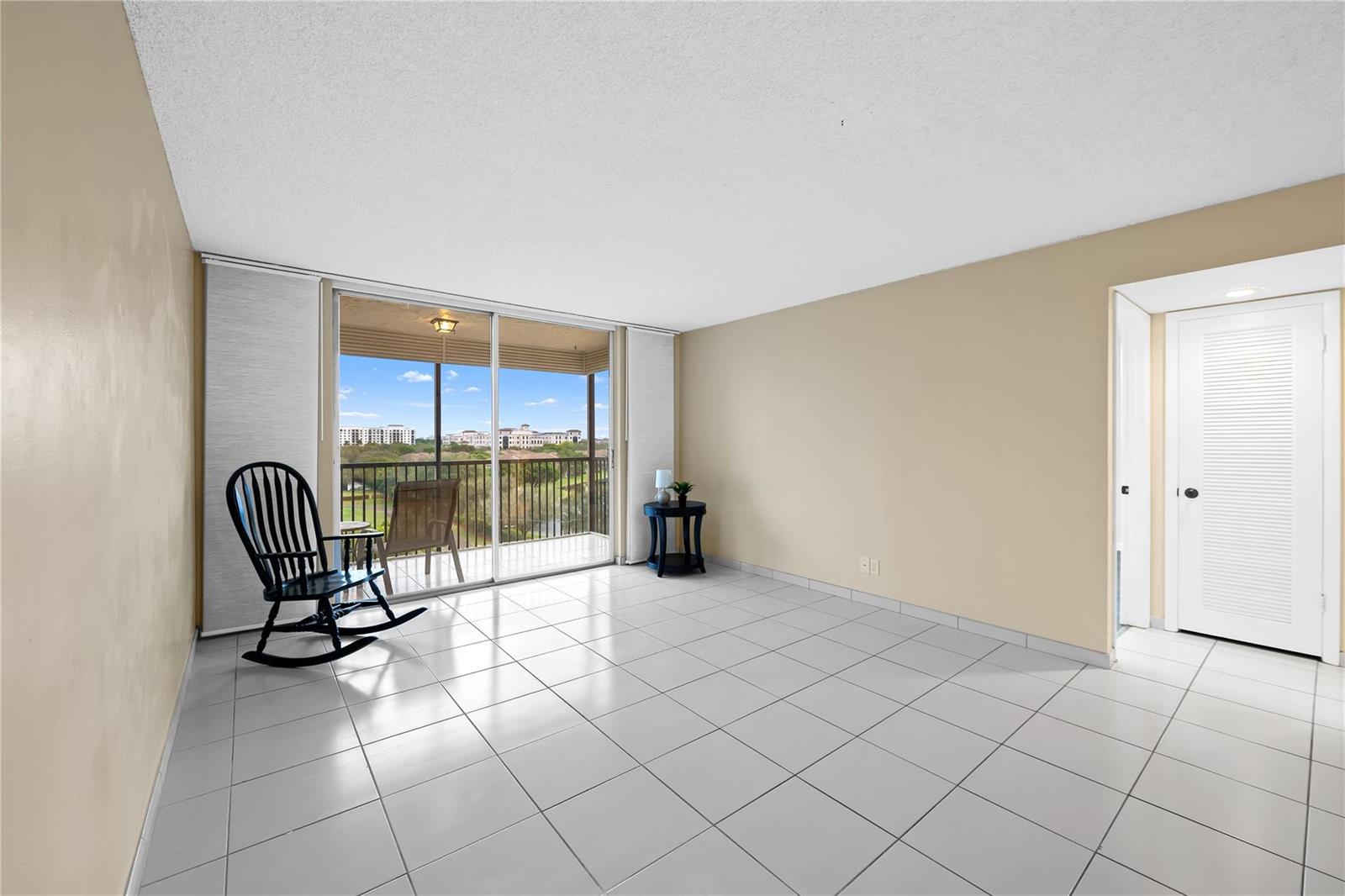 A tiled living room features a sliding glass door leading to a balcony with views — 3300 W Rolling Hills Circle # 610, Davie FL 33328, DAVIE, FL
