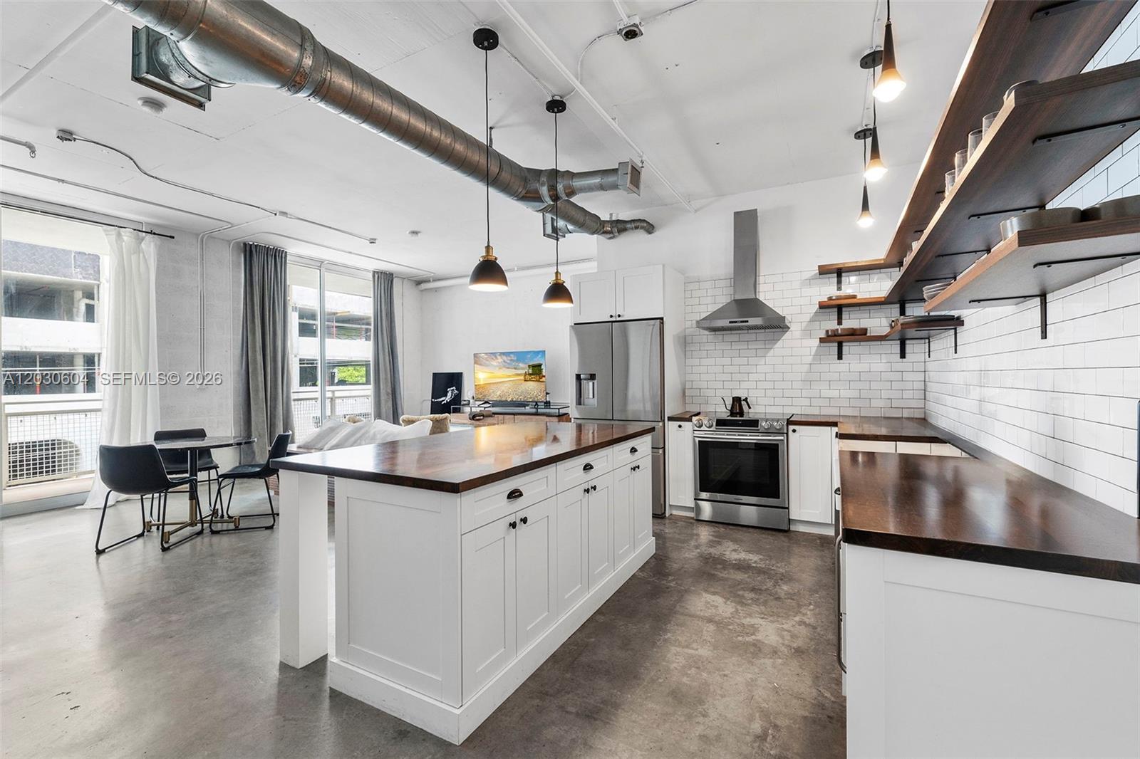 An industrial-style kitchen features white cabinets, dark wood countertops, open shelving, and exposed ceiling ductwork — 444 NE 30th St # 402, Miami FL 33137, MIAMI, FL