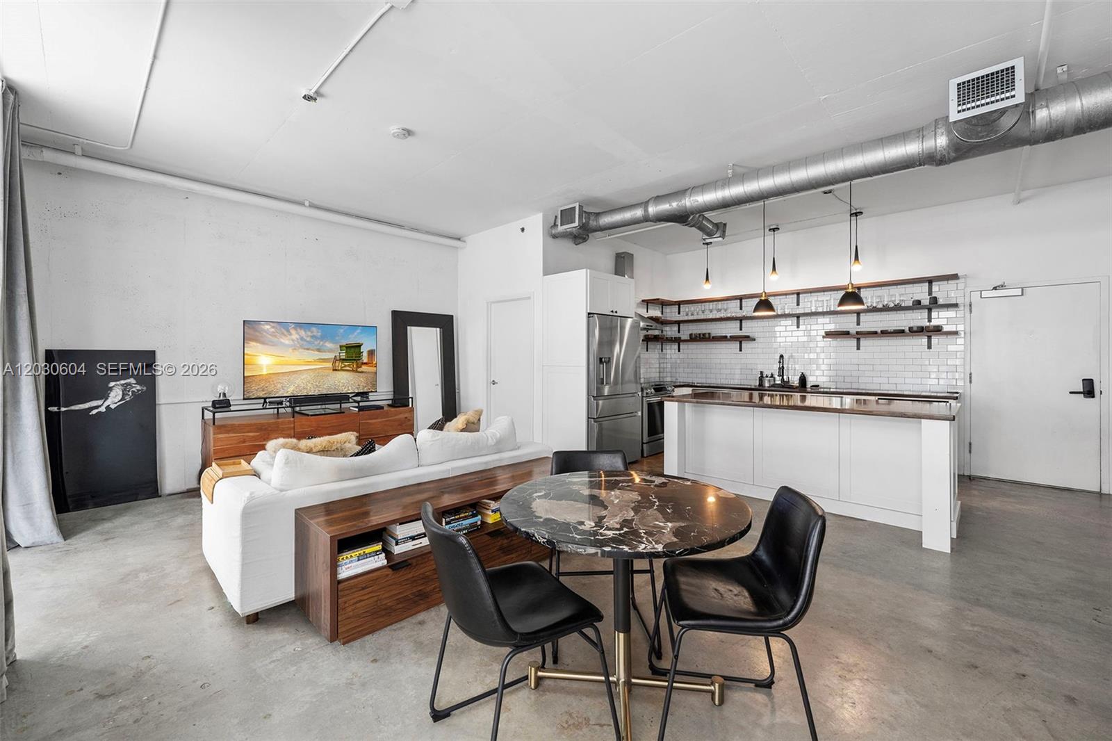 An open-concept loft features a kitchen with white cabinetry, a dining area, and living space — 444 NE 30th St # 402, Miami FL 33137, MIAMI, FL