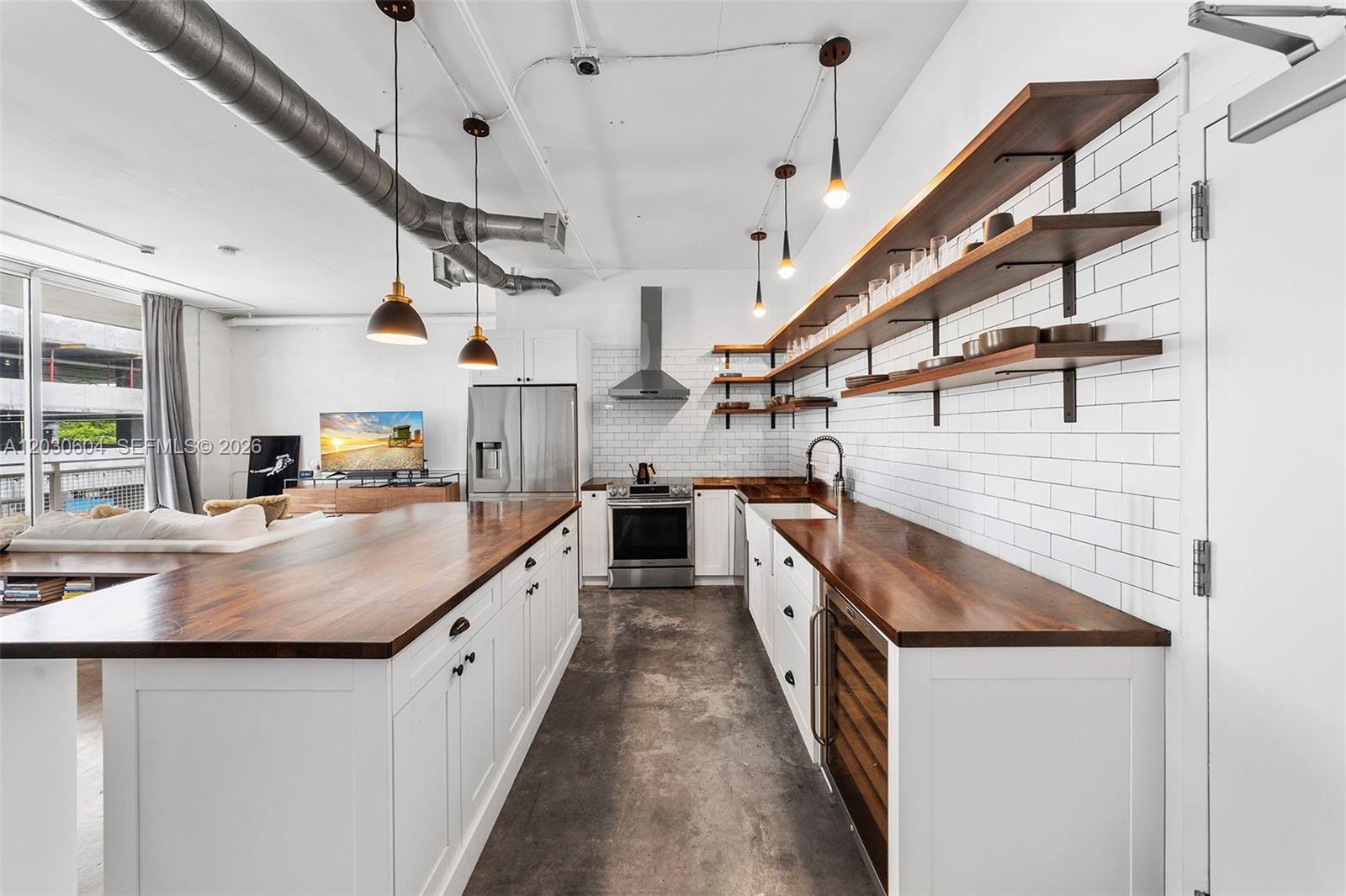 A modern kitchen features white cabinets, wood countertops, open shelving, and exposed industrial ductwork — 444 NE 30th St # 402, Miami FL 33137, MIAMI, FL