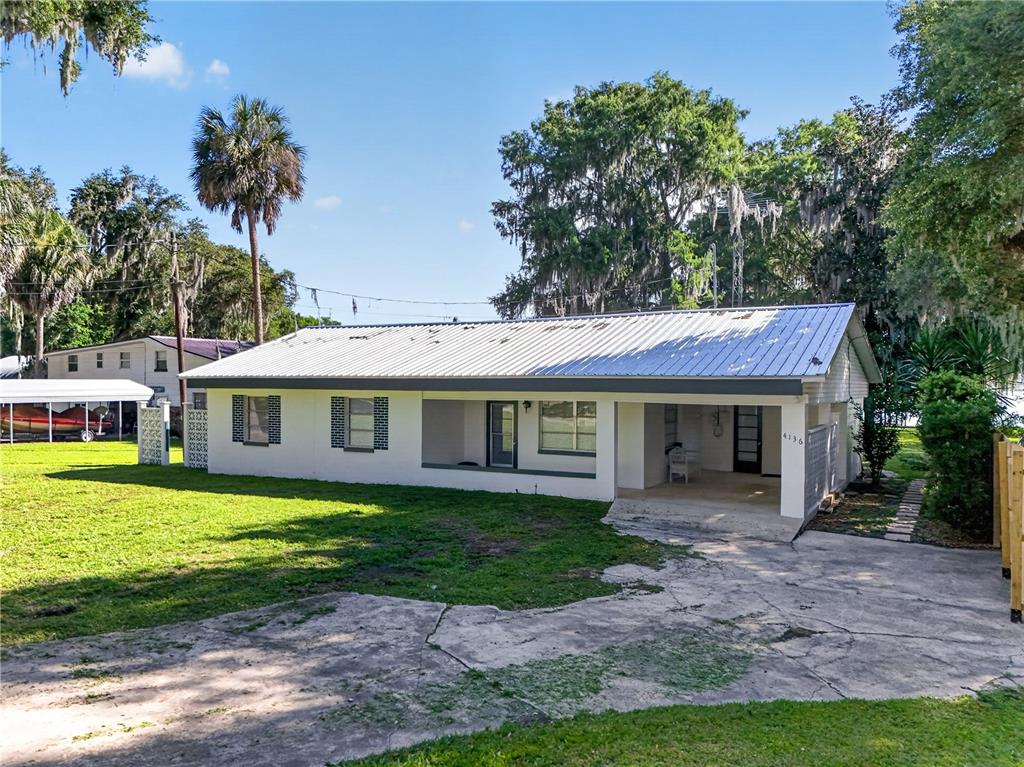 A single-story house with a white exterior, metal roof, and a concrete driveway — 4136 CR 400, LAKE PANASOFFKEE, FL