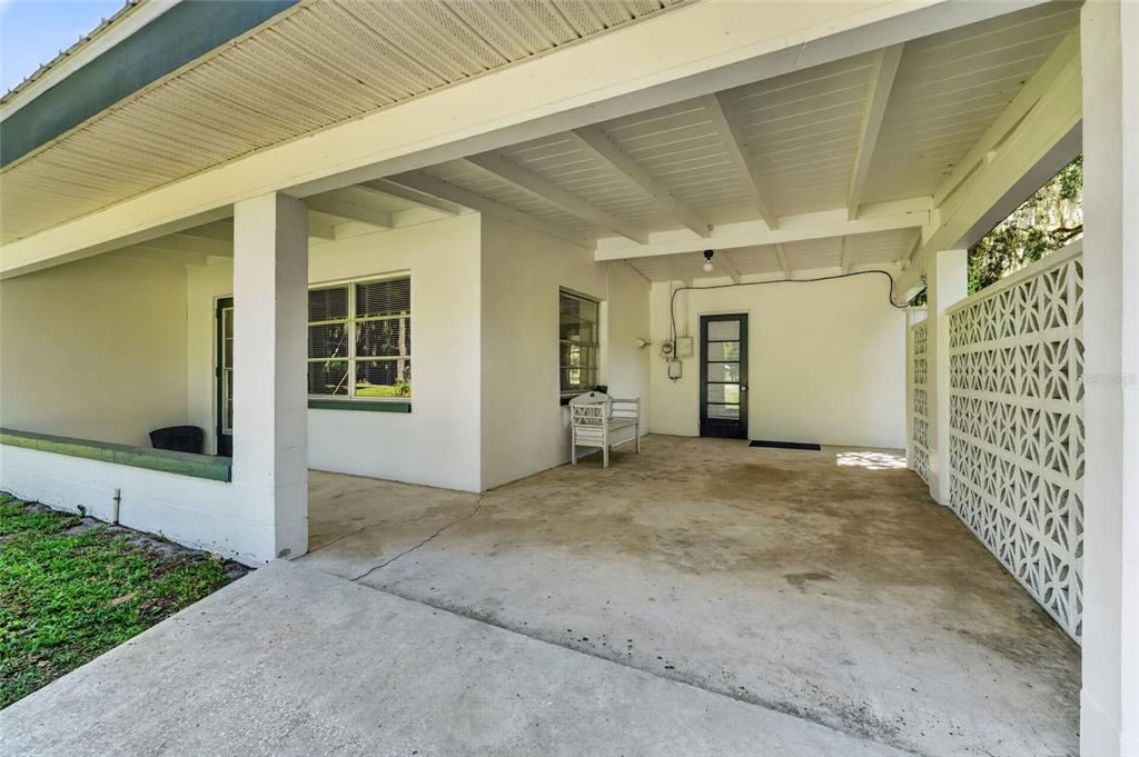 A covered concrete patio features a white bench, a glass-paneled door, and decorative lattice walls — 4136 CR 400, LAKE PANASOFFKEE, FL