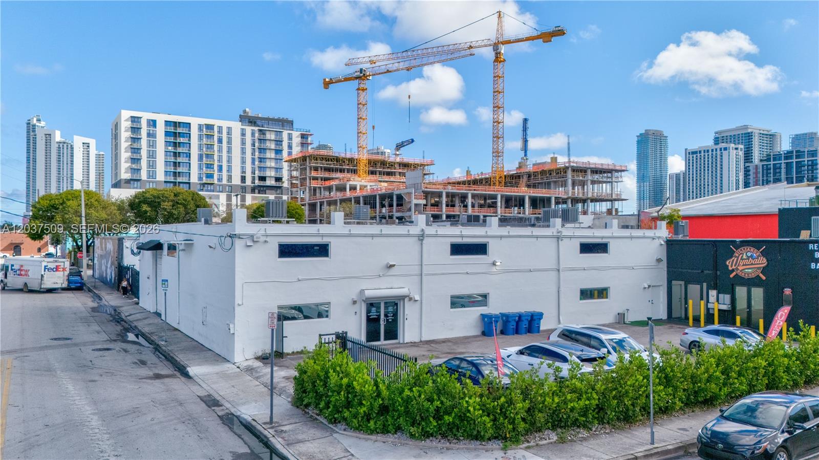 An exterior view of a white commercial building with a parking lot and construction cranes — 2045 NW 1st Ave, Miami FL 33127, MIAMI, FL