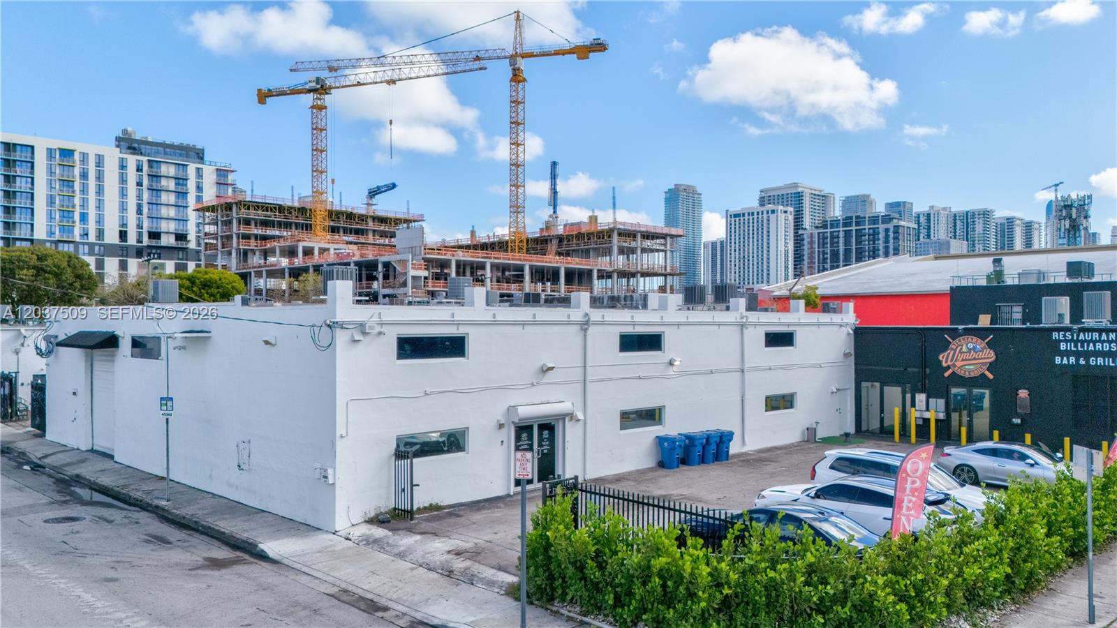 A white commercial building stands in front of a construction site with tall cranes — 2045 NW 1st Ave, Miami FL 33127, MIAMI, FL