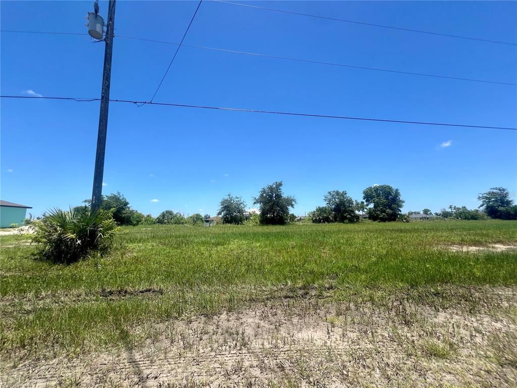 A grassy, vacant lot features a utility pole on the left under a clear sky — 2229 NW 9TH TERRACE, CAPE CORAL, FL