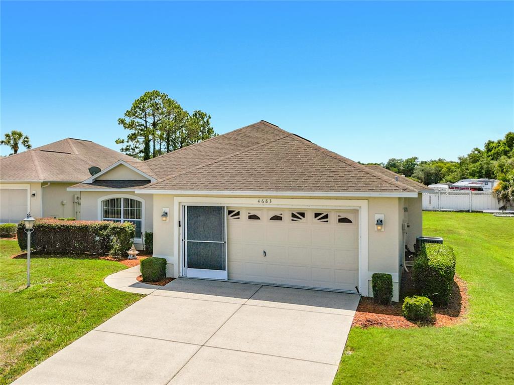 A single-story house exterior features a beige stucco facade, a two-car garage, and a driveway — 4683 N LAKE VISTA TRAIL, HERNANDO, FL