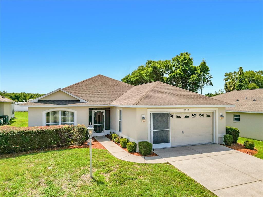 A single-story suburban house with a beige stucco exterior, a brown shingled roof, and a driveway — 4683 N LAKE VISTA TRAIL, HERNANDO, FL