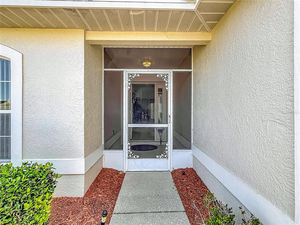 A concrete walkway leads to a white front door with a decorative screen — 4683 N LAKE VISTA TRAIL, HERNANDO, FL