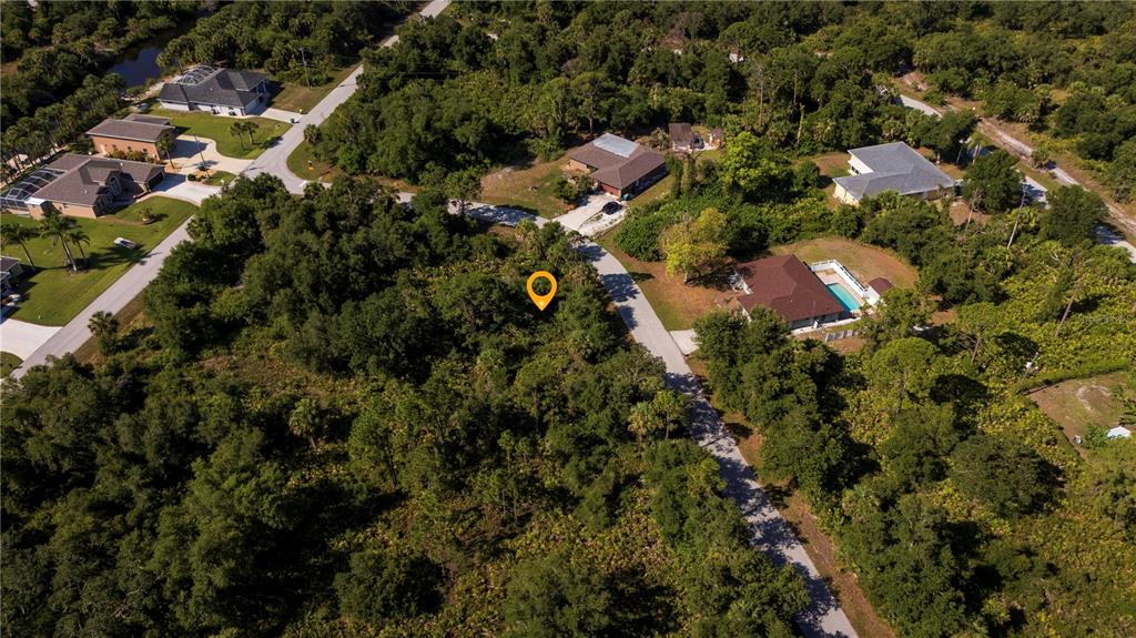 An aerial view shows a vacant, wooded lot marked by a pin in a residential neighborhood — 3266 GABOR STREET, PORT CHARLOTTE, FL