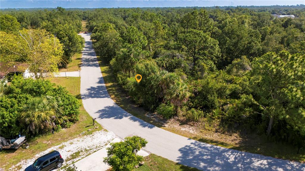An aerial view shows a paved road winding through a wooded area with a yellow pin — 3266 GABOR STREET, PORT CHARLOTTE, FL