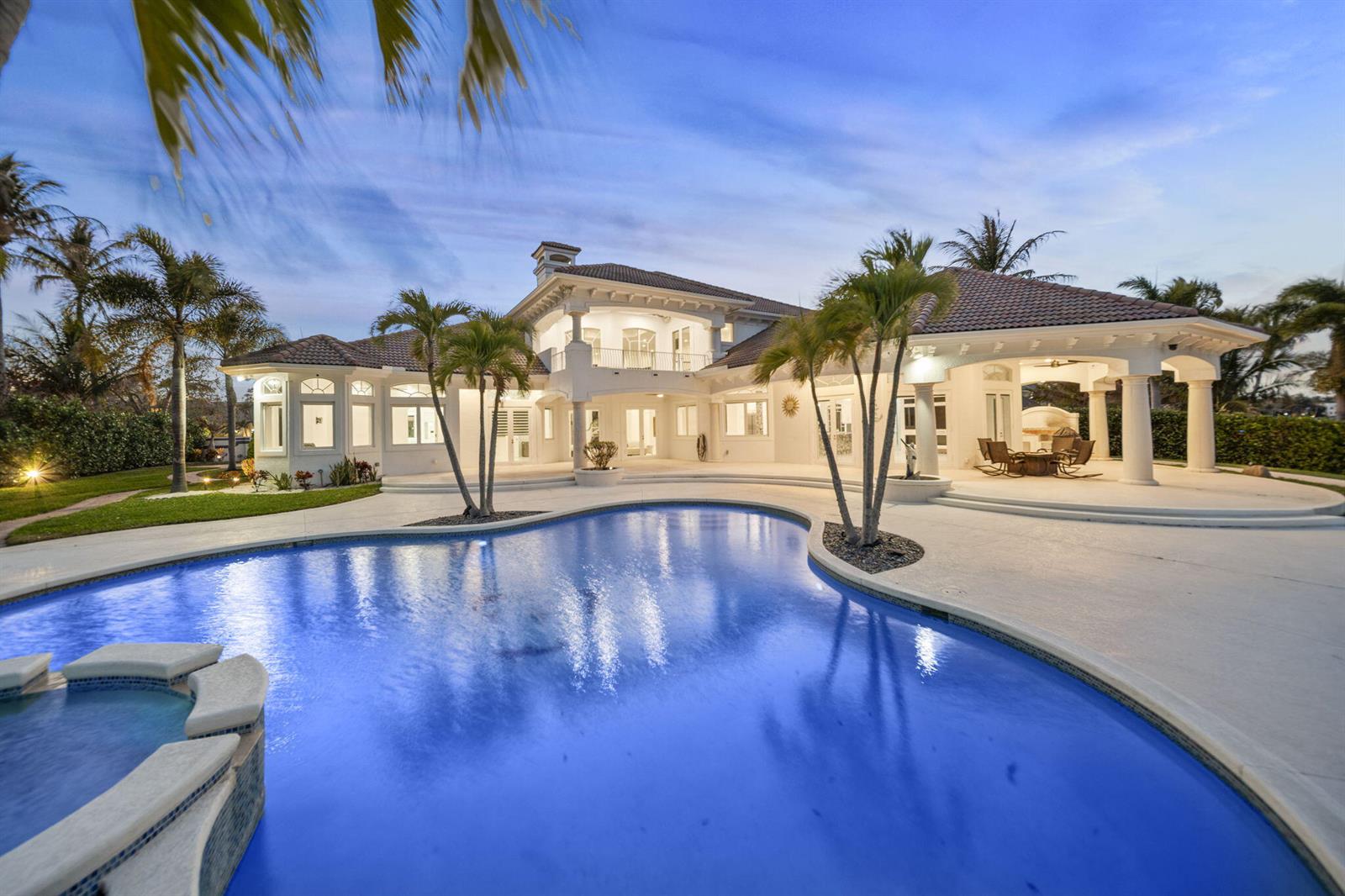A large white two-story house with a pool, patio, and palm trees at dusk — 1735 SE St Lucie Boulevard, Stuart FL 34996, STUART, FL