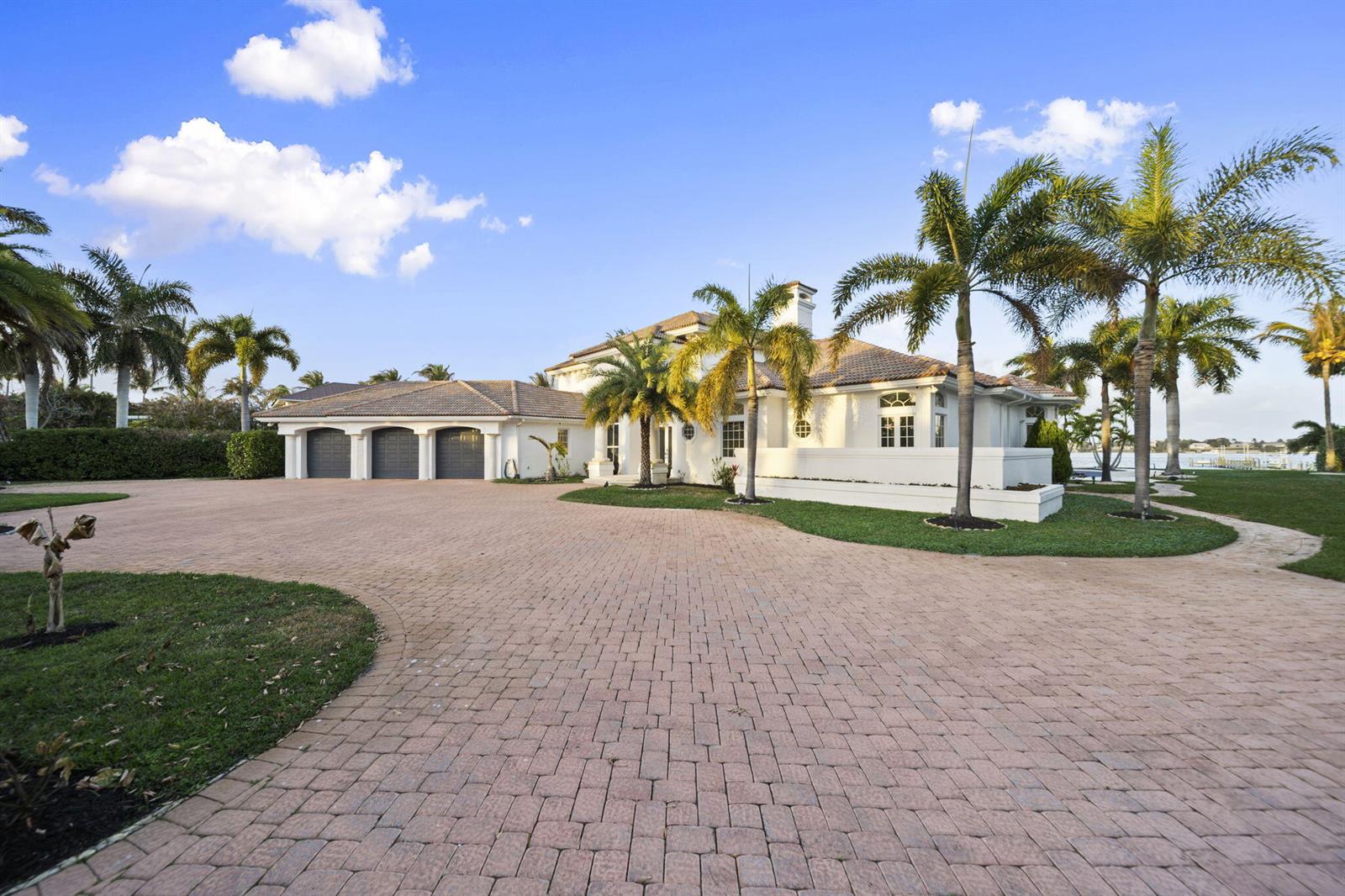 A large white house with a three-car garage and a paved driveway surrounded by palms — 1735 SE St Lucie Boulevard, Stuart FL 34996, STUART, FL
