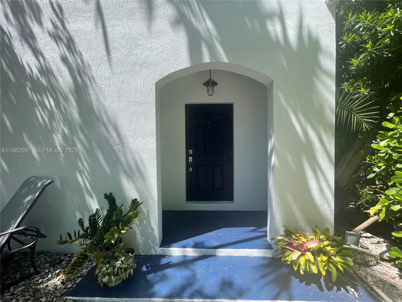A black front door is recessed within an arched entryway featuring blue painted concrete steps — 3421 SW 25th St # 01, Miami FL 33133, MIAMI, FL