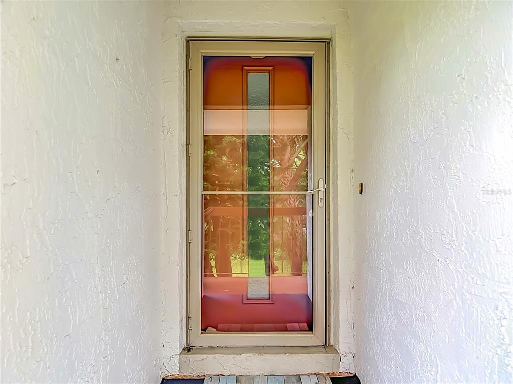 A beige storm door is set within a white textured wall at an entryway — 12308 EAGLESWOOD DRIVE UNIT D, HUDSON, FL